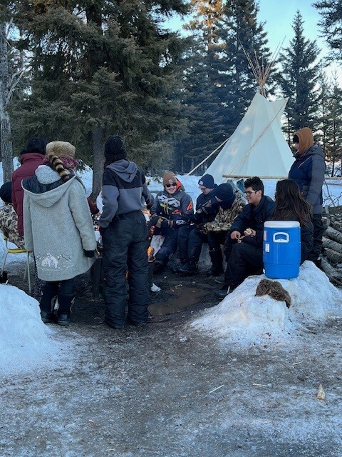 Image of CPE students and staff gathered around a camp fire.